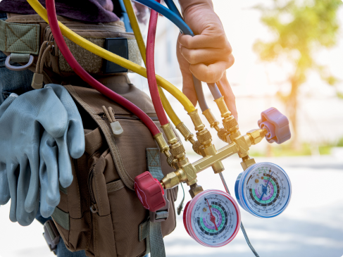 A person holding a tool belt with hoses and gauges.
