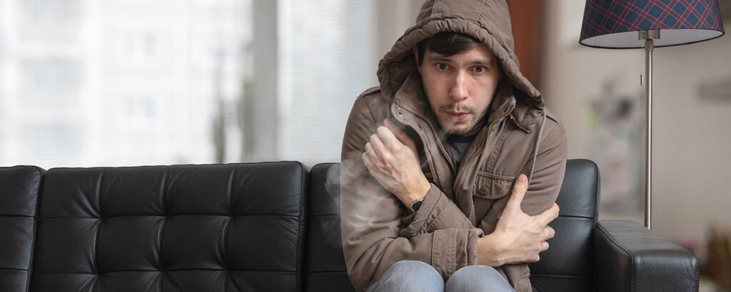 man wearing coat shivering on sofa