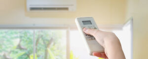 %Focuskw% | Tri-City Air Conditioning Co. person using remote for HVAC wall unit